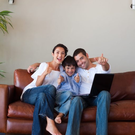 Padres e hijos divirtiéndose con una computadora portátil en casa.